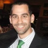 Portrait de Manuel Neuhauser avec une veste de costume noire, une chemise à rayures fines et une cravate verte