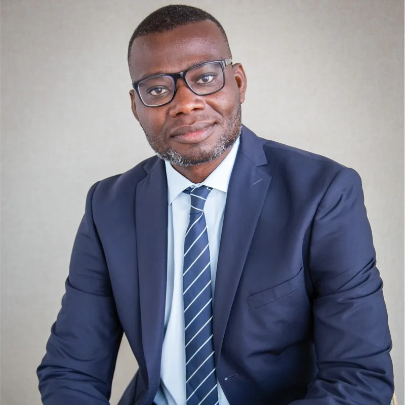 Portrait de Markendy Vilmeus, avec chemise blanche, cravate à rayures et veste de costume bleu foncé